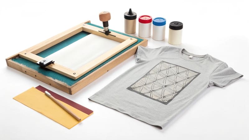 Cost of Beginner vs. Professional Screen Printing Setup A simple, affordable beginner's screen printing kit next to a much larger, professional multi-color press.