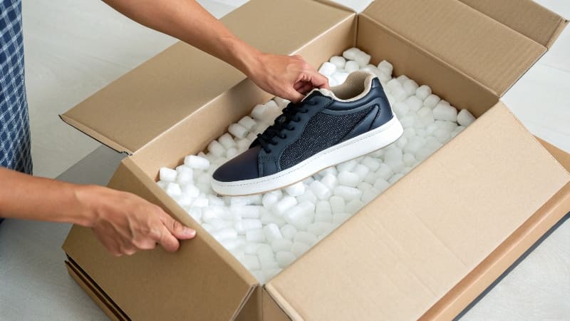 A large wooden shipping crate being carefully loaded onto a freight truck with a forklift.